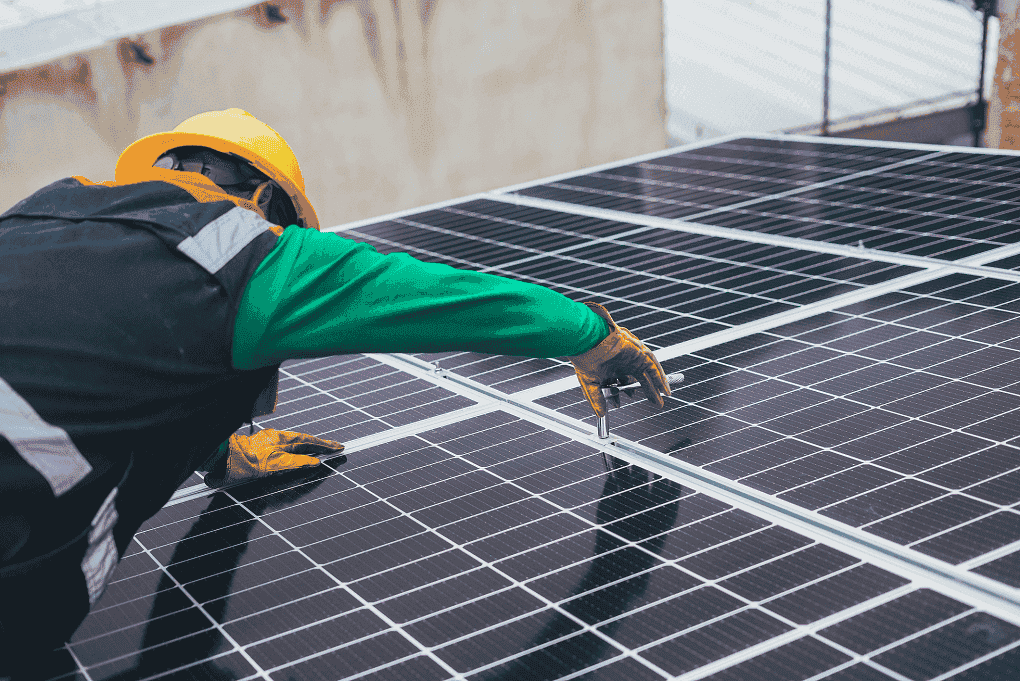 Photo of an employee on a roof installing solar panels. this is for the Sustainability policy.